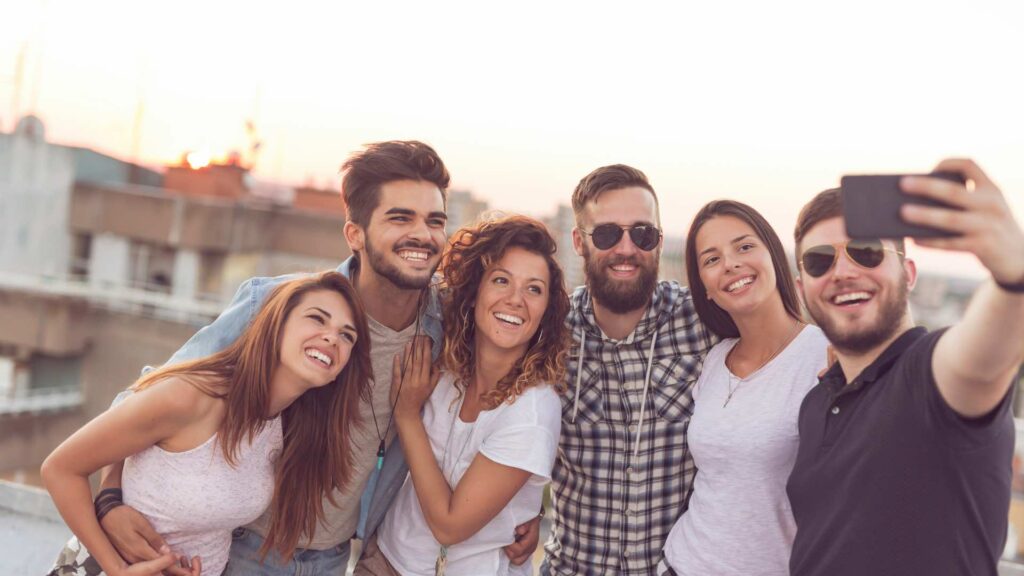 Group Of Six People Smiling And Taking A Selfie