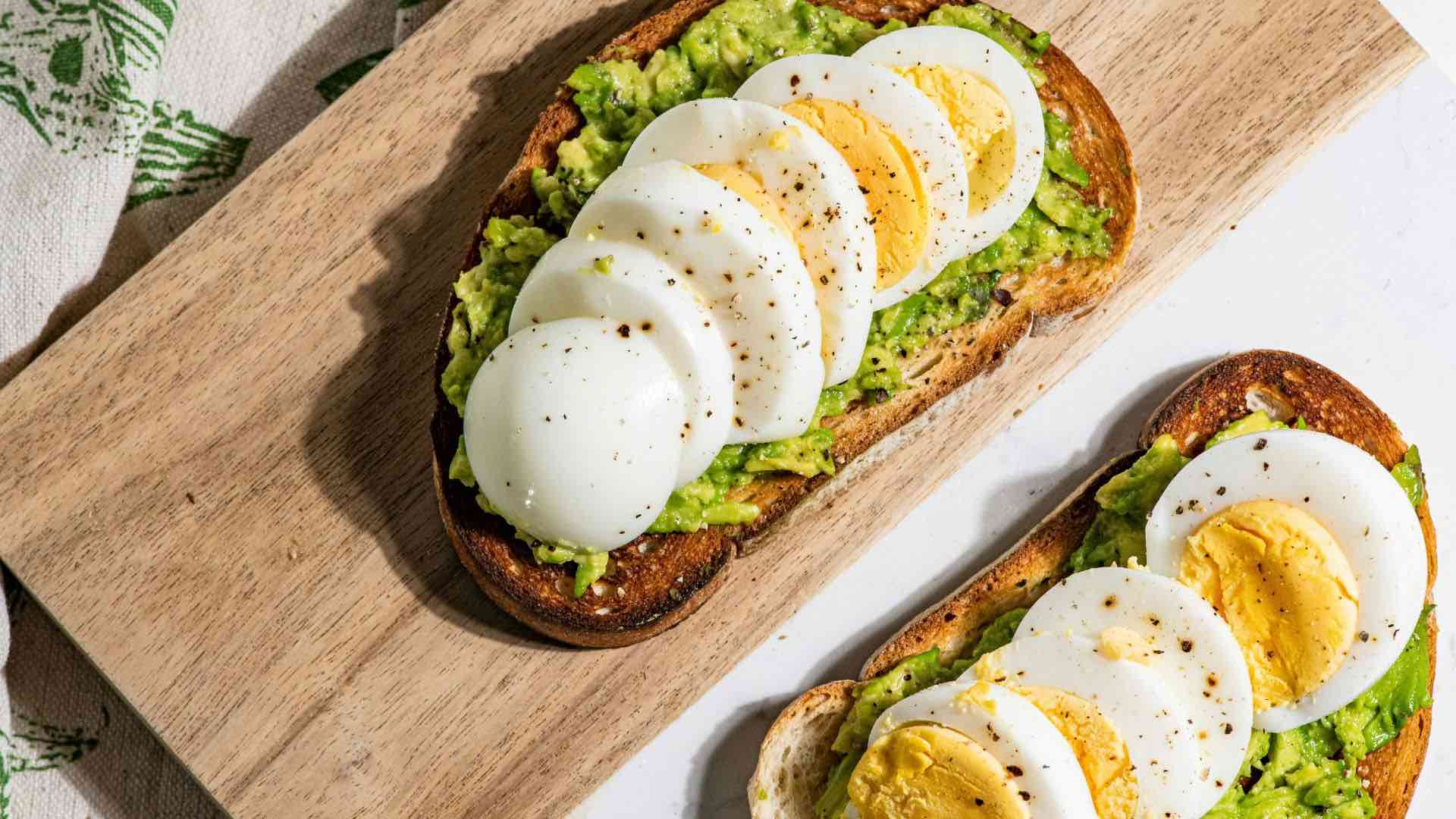 Toast On Cutting Board With Avocado And Sliced Boiled Eggs