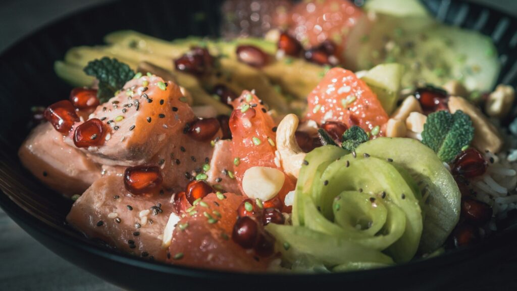 Bowl With Salmon, Cucumber, Pomegranate Seeds, And Other Fruits And Vegetables