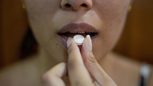 Woman Putting Painkiller Tablet In Mouth