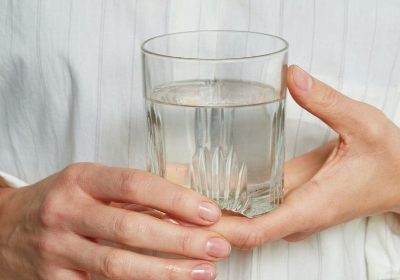 Person Holding Glass Of Water In Front Of Chest