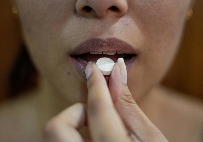 Woman Putting Painkiller Tablet In Mouth