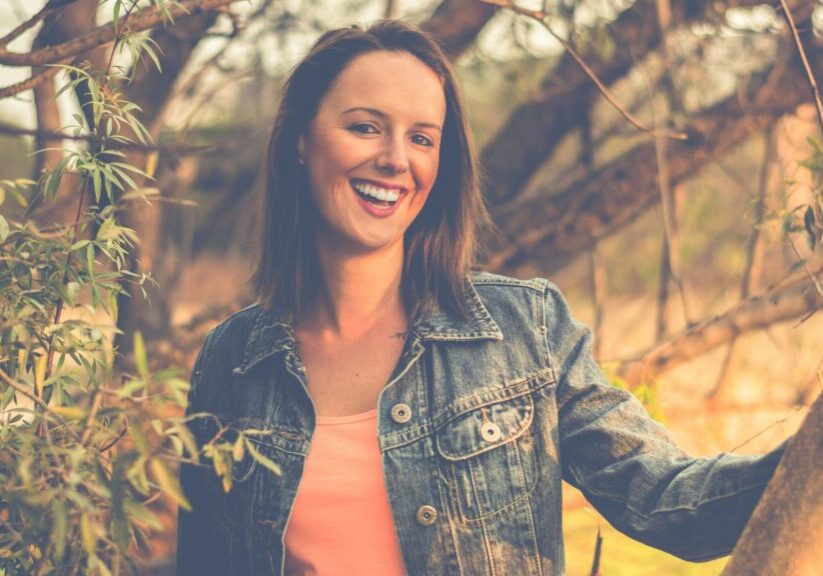 Woman In Denim Jacket Smiling With Trees In The Background