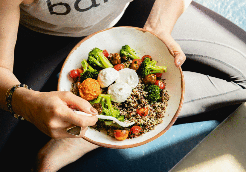 Woman Sitting Cross-Legged With Bowl Of Healthy Food