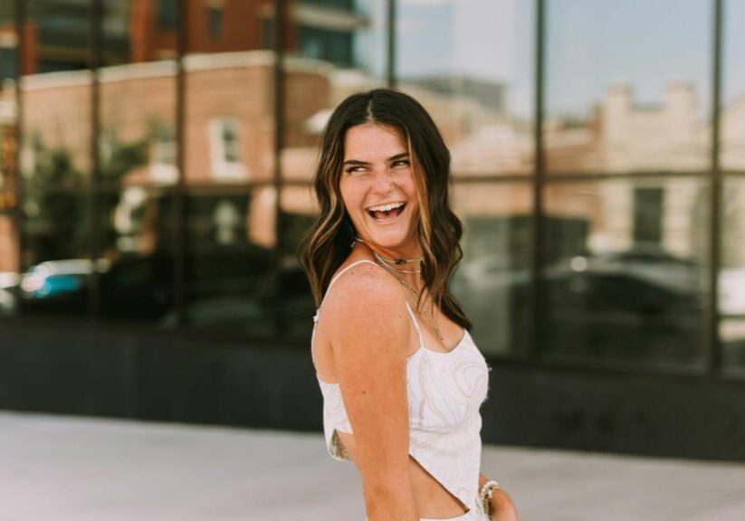 Woman In White Top Looking Behind Shoulder And Laughing