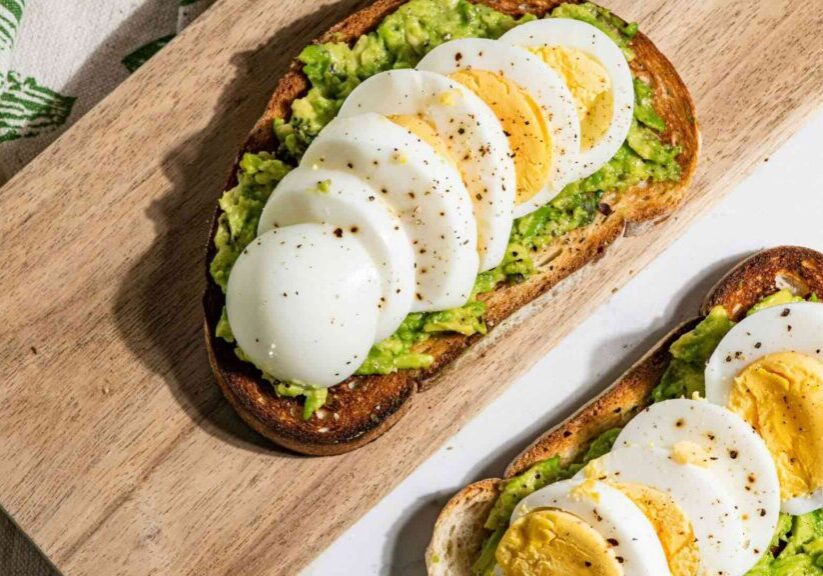 Toast On Cutting Board With Avocado And Sliced Boiled Eggs