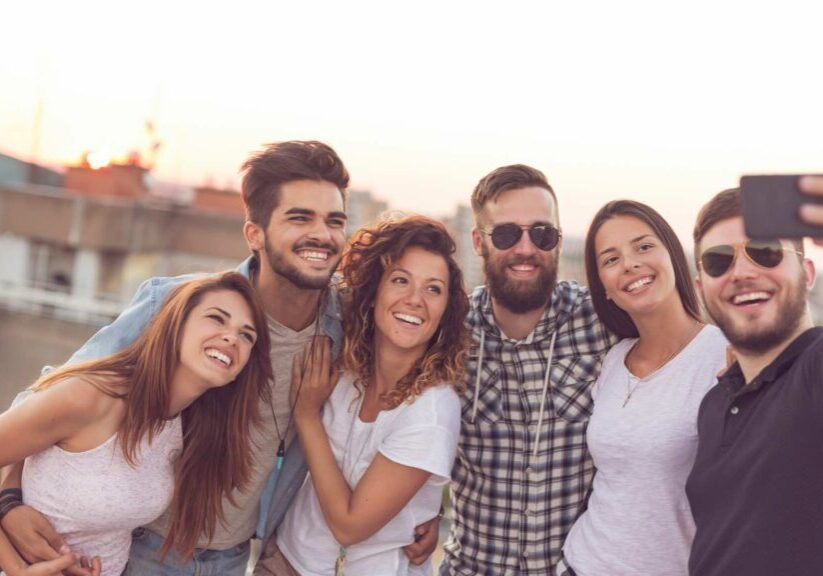 Group Of Six People Smiling And Taking A Selfie